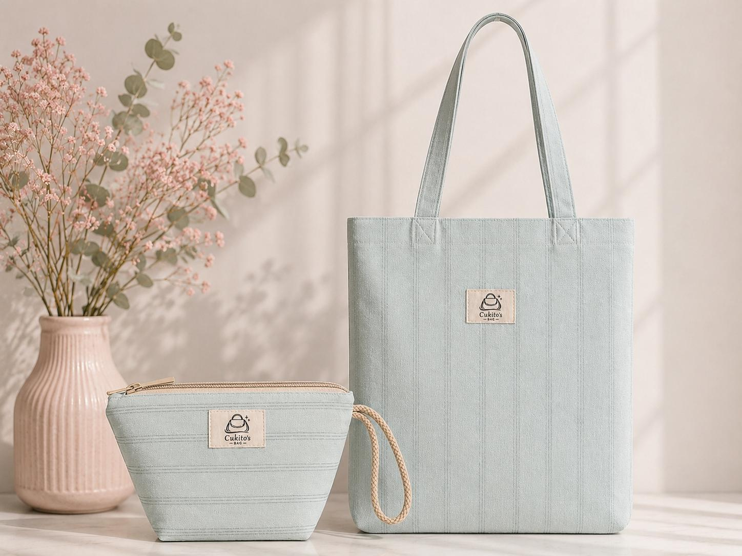 Bolsa tote y neceser azul claro de Cukito's Bag sobre fondo beige