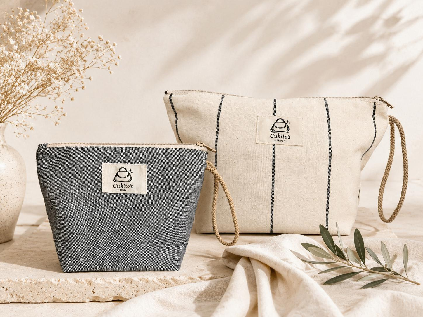 Neceseres gris y crema de Cukito's Bag junto a una rama de olivo